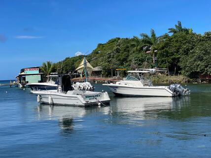 A man and woman holding sidewise a large colorful Mahi on board the fishing boat on a clear day